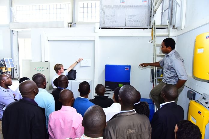 Engineer Evan Kimani explains the SMA inverter to trainees at the SERC Lab at Strathmore University